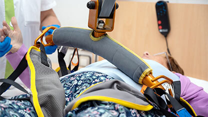 A care staff using a power assist to lifts a patient at nursing home. High quality photo 